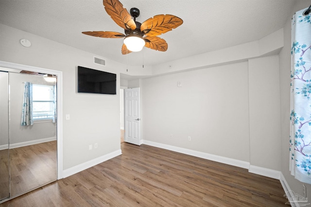 unfurnished bedroom featuring hardwood / wood-style flooring, ceiling fan, a textured ceiling, and a closet