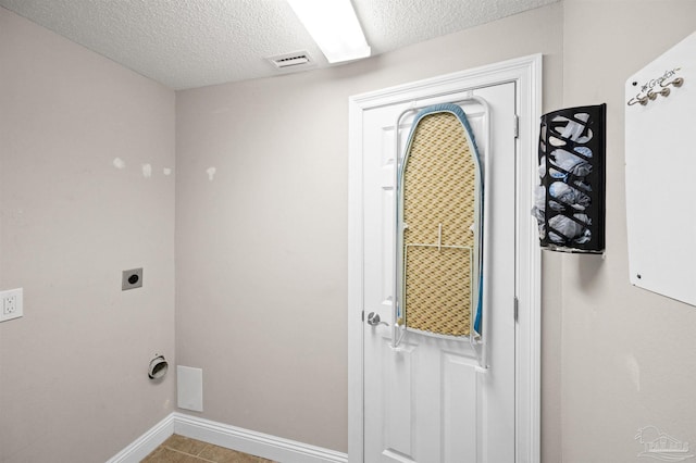 washroom with a textured ceiling, tile patterned floors, and electric dryer hookup