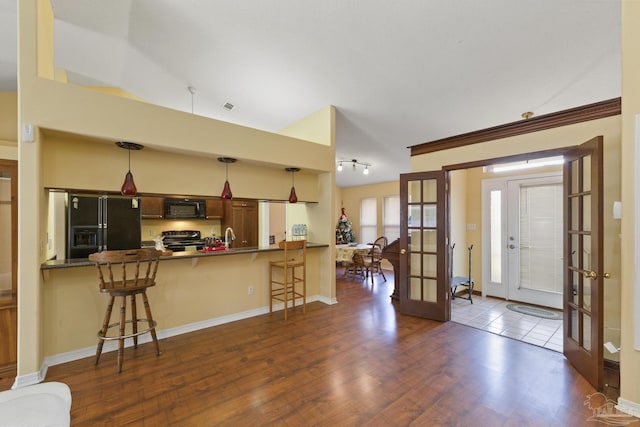 kitchen featuring french doors, a kitchen bar, kitchen peninsula, pendant lighting, and black appliances