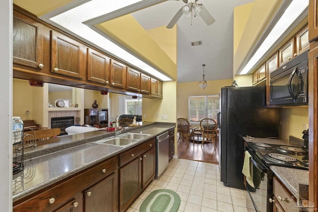 kitchen featuring sink, a tile fireplace, ceiling fan, black appliances, and light tile patterned flooring