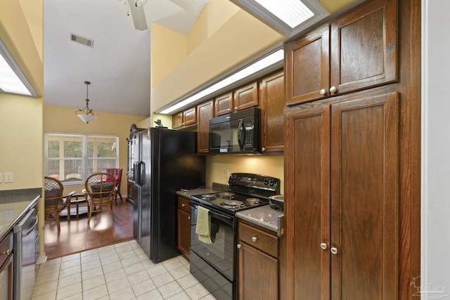 kitchen with pendant lighting, vaulted ceiling, black appliances, and light tile patterned flooring