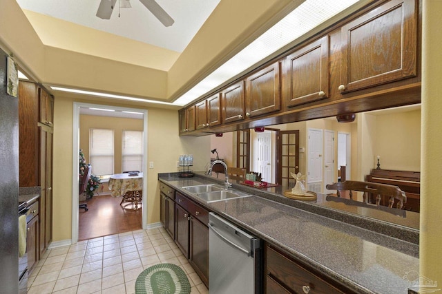 kitchen featuring sink, light tile patterned floors, stainless steel dishwasher, a raised ceiling, and ceiling fan