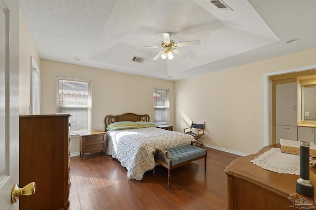 bedroom featuring ceiling fan, a textured ceiling, dark hardwood / wood-style flooring, and a tray ceiling