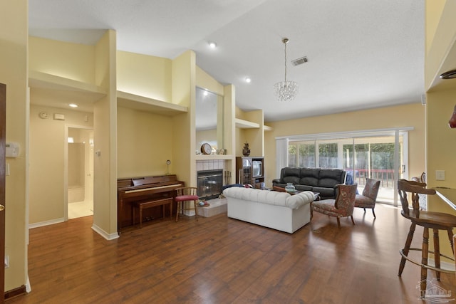 living room featuring dark wood-type flooring, an inviting chandelier, a fireplace, and high vaulted ceiling