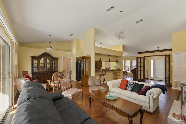 living room featuring lofted ceiling, dark wood-type flooring, and an inviting chandelier