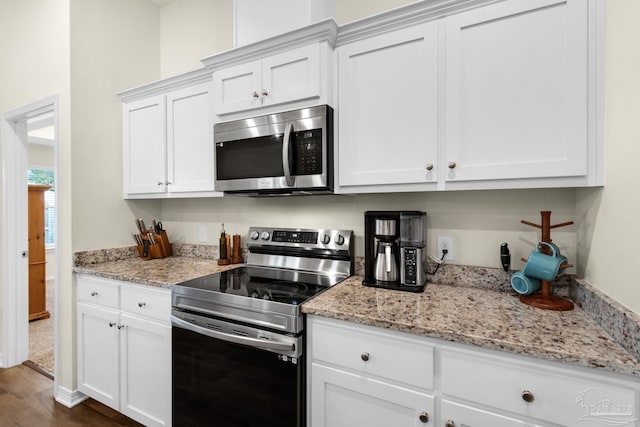 kitchen with light stone counters, stainless steel appliances, dark wood-style floors, and white cabinetry