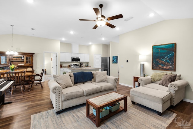 living room with ceiling fan with notable chandelier, vaulted ceiling, wood finished floors, and visible vents