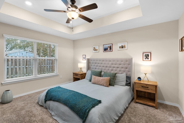 carpeted bedroom with a tray ceiling, recessed lighting, and baseboards