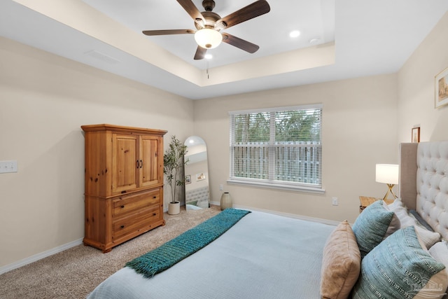 bedroom featuring a tray ceiling, baseboards, light carpet, and ceiling fan