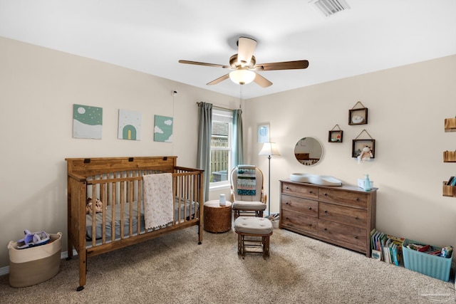 bedroom with visible vents, carpet flooring, a nursery area, and ceiling fan