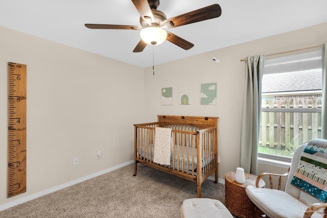 carpeted bedroom featuring baseboards, a nursery area, and a ceiling fan