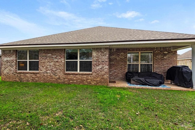 rear view of house with a yard, a patio, and brick siding