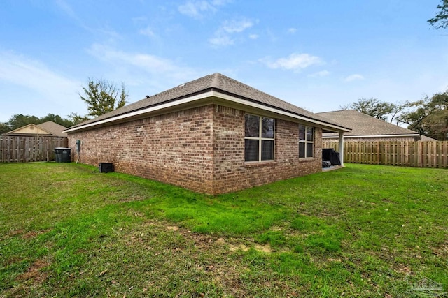 view of home's exterior with brick siding, a fenced backyard, and a yard