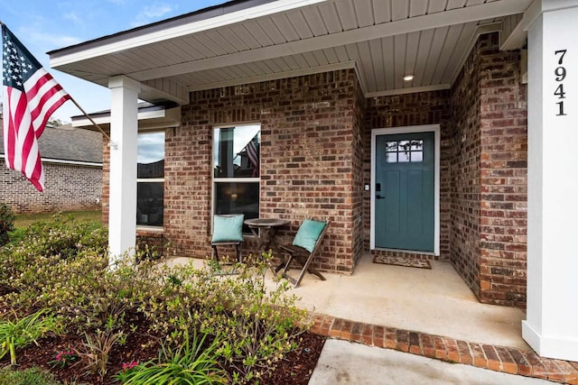 entrance to property featuring brick siding and covered porch