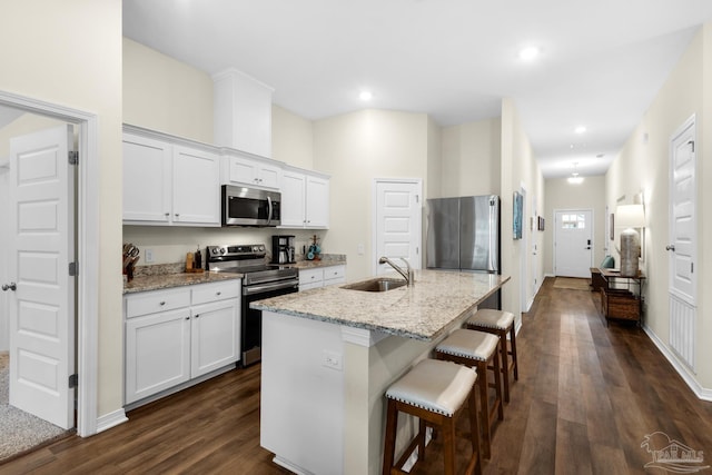 kitchen featuring a sink, stainless steel appliances, dark wood-type flooring, and a breakfast bar