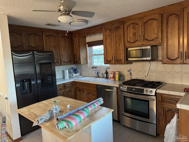 8156 Pompano St, Navarre, FL 32566 - kitchen with a sink, stainless steel appliances, tile countertops, light tile patterned floors, and visible vents