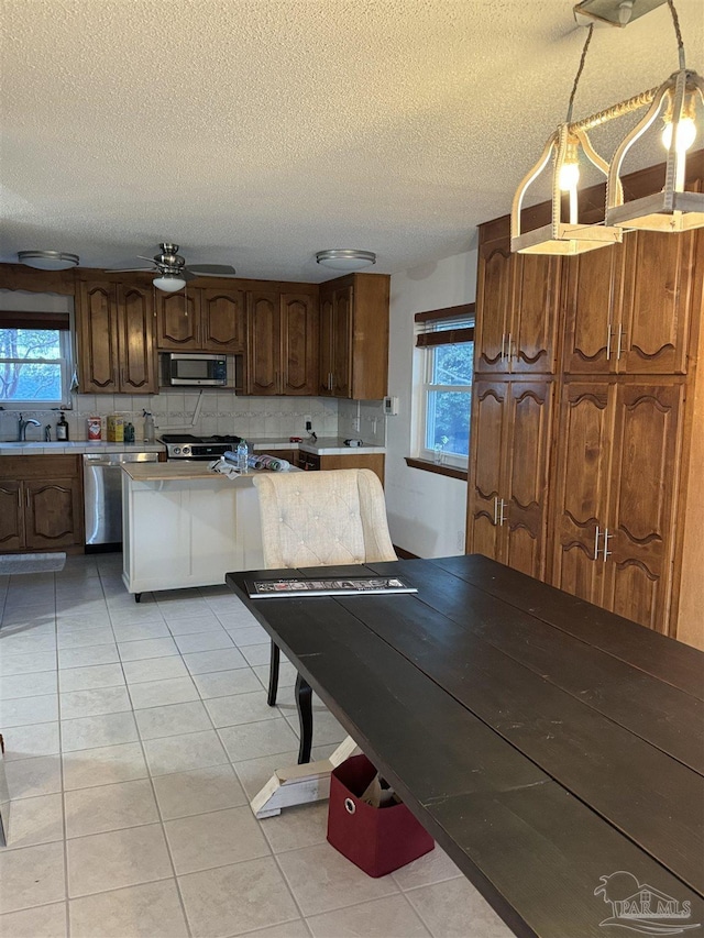 8156 Pompano St, Navarre, FL 32566 - kitchen featuring light countertops, a textured ceiling, light tile patterned flooring, and stainless steel appliances