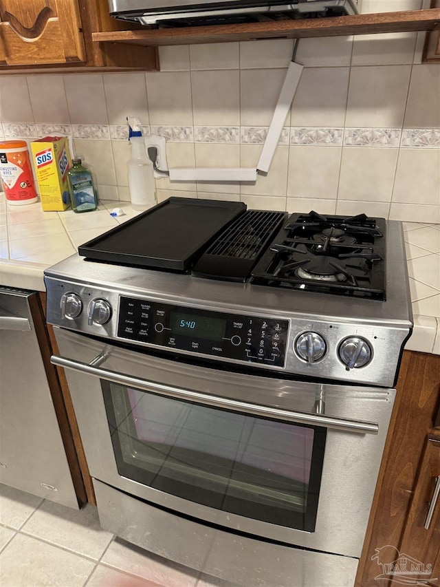 8156 Pompano St, Navarre, FL 32566 - kitchen featuring light countertops, appliances with stainless steel finishes, decorative backsplash, and light tile patterned floors