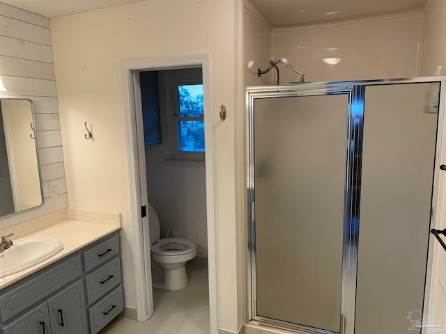 bathroom featuring tile patterned flooring, vanity, toilet, and a shower with door