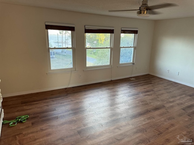 8156 Pompano St, Navarre, FL 32566 - spare room featuring baseboards, dark wood-style flooring, ceiling fan, and a healthy amount of sunlight