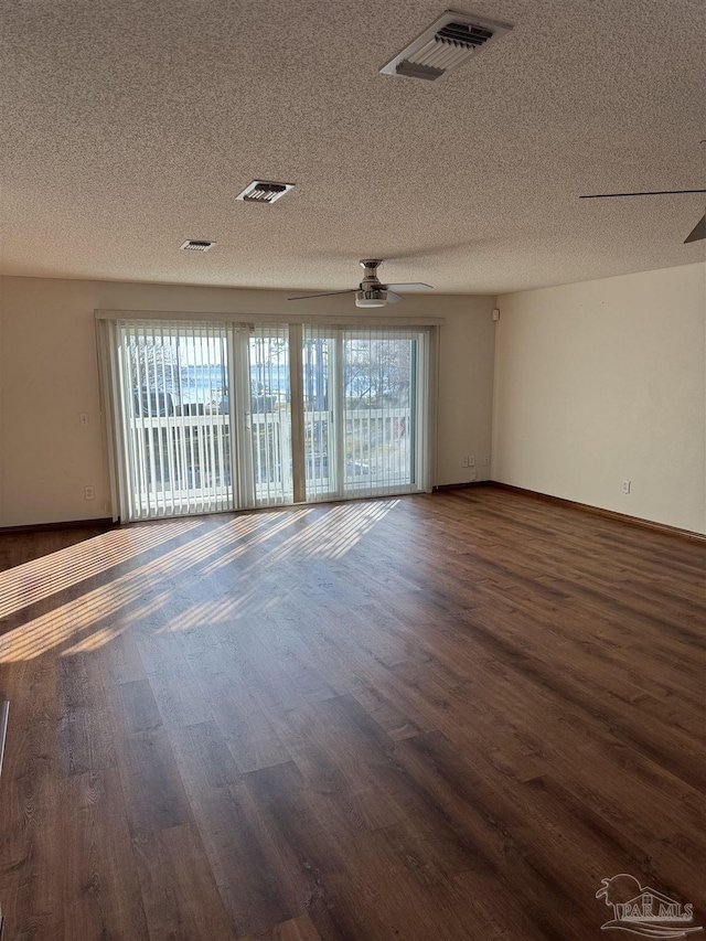 unfurnished room with a wealth of natural light, ceiling fan, and dark wood-type flooring