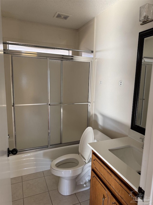 full bathroom with bath / shower combo with glass door, a textured ceiling, vanity, tile patterned flooring, and toilet