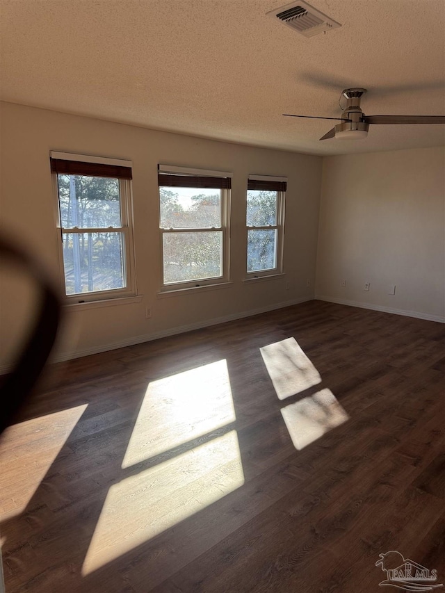 empty room with ceiling fan, dark hardwood / wood-style flooring, and a textured ceiling