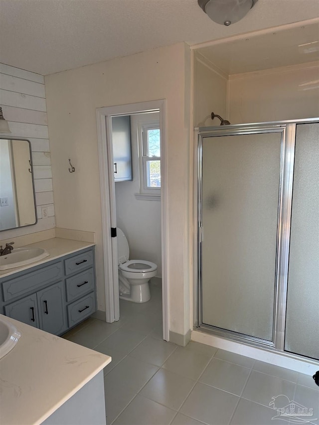 bathroom featuring tile patterned flooring, a shower with door, vanity, and toilet