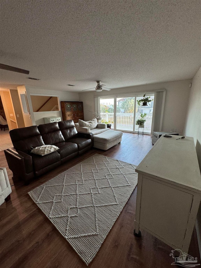 living room featuring wood-type flooring, a textured ceiling, and ceiling fan