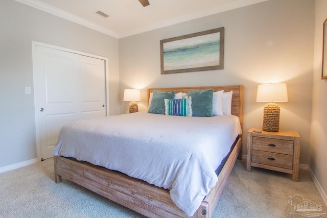 carpeted bedroom with baseboards, visible vents, a ceiling fan, crown molding, and a closet