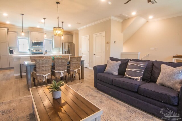 living room with light hardwood / wood-style flooring, a chandelier, and ornamental molding