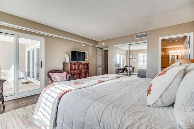 bedroom with visible vents, wood finished floors, access to exterior, a textured ceiling, and a closet