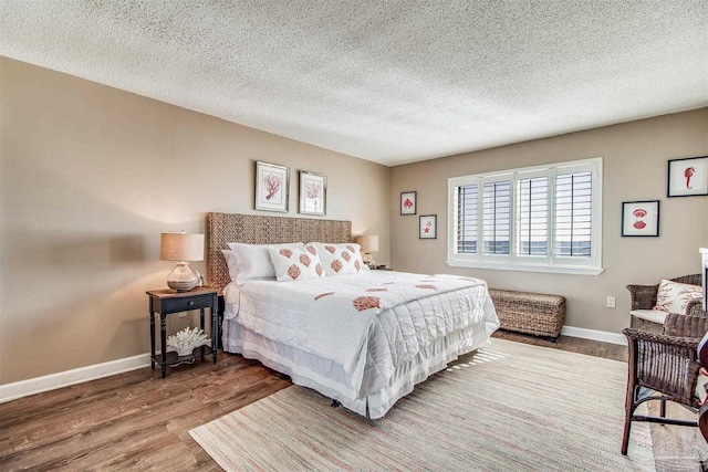 bedroom with a textured ceiling, baseboards, and wood finished floors