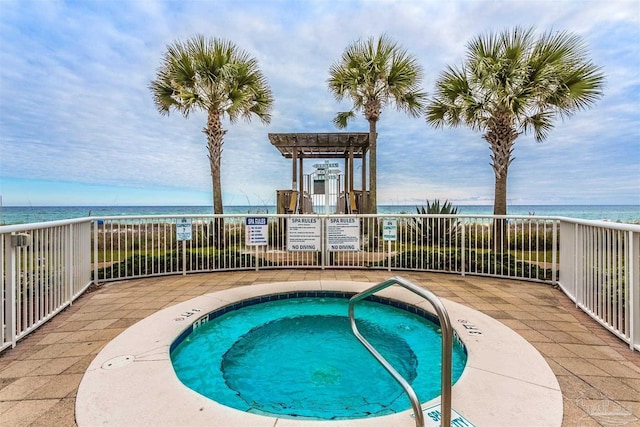 view of pool with a water view and a hot tub