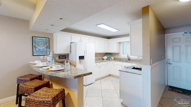 kitchen featuring light tile patterned floors, a peninsula, a kitchen breakfast bar, white cabinets, and white fridge with ice dispenser