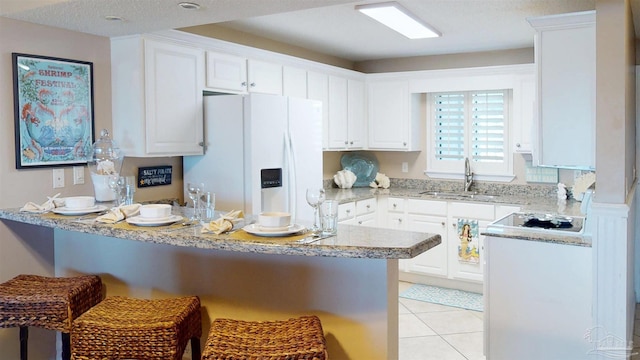 kitchen featuring light tile patterned floors, a kitchen breakfast bar, a peninsula, white fridge with ice dispenser, and a sink