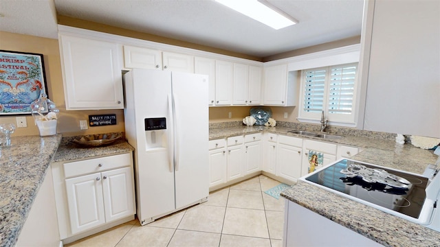 kitchen featuring white fridge with ice dispenser, white cabinets, a sink, and light tile patterned flooring