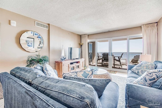 tiled living room featuring visible vents and a textured ceiling