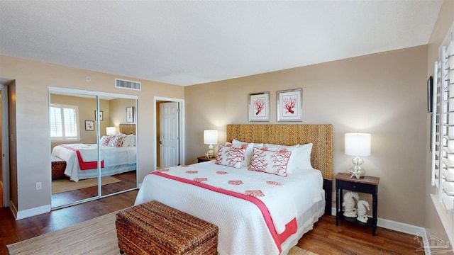 bedroom featuring baseboards, visible vents, a closet, and wood finished floors