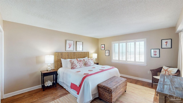 bedroom featuring a textured ceiling, baseboards, and wood finished floors