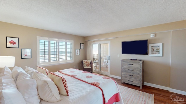 bedroom featuring access to outside, a textured ceiling, baseboards, and wood finished floors