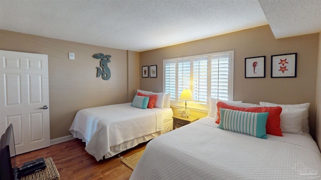 bedroom featuring a textured ceiling, baseboards, and wood finished floors