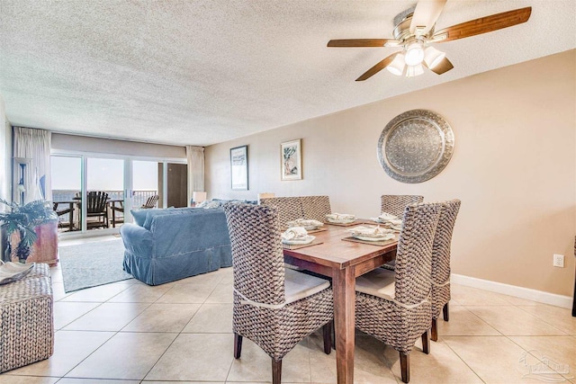 dining area featuring light tile patterned floors, ceiling fan, baseboards, and a textured ceiling