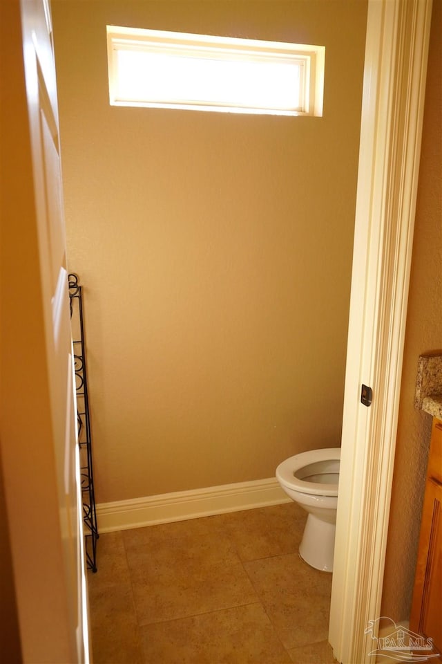 bathroom with tile patterned flooring, vanity, toilet, and a wealth of natural light