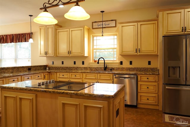 kitchen with dark stone countertops, stainless steel appliances, a center island, decorative light fixtures, and sink