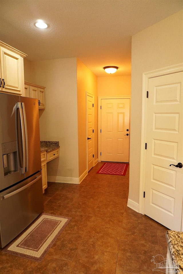 kitchen with built in desk, stone countertops, and stainless steel fridge with ice dispenser