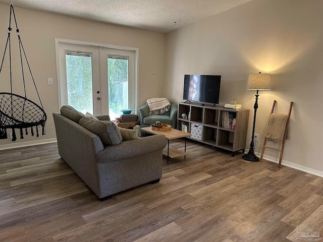 living room featuring a textured ceiling, dark wood-type flooring, and french doors