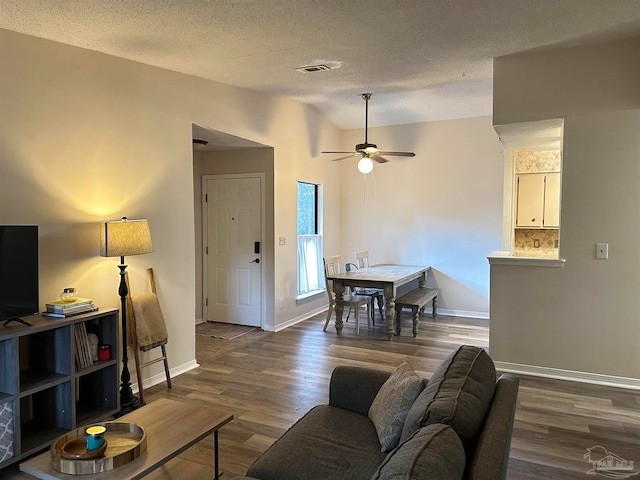 living room featuring ceiling fan, a textured ceiling, and dark hardwood / wood-style flooring