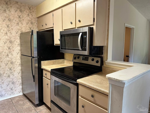 kitchen featuring vaulted ceiling, a textured ceiling, appliances with stainless steel finishes, and light tile patterned floors