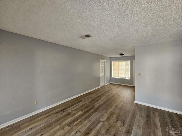 unfurnished room featuring dark wood-type flooring and a textured ceiling